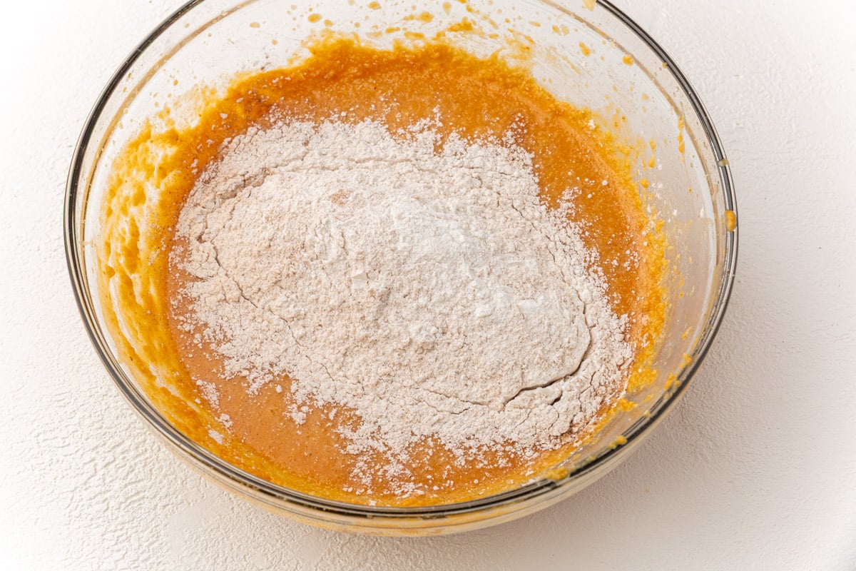 Gluten-free flour mixture added to pumpkin batter in a bowl before final mixing.