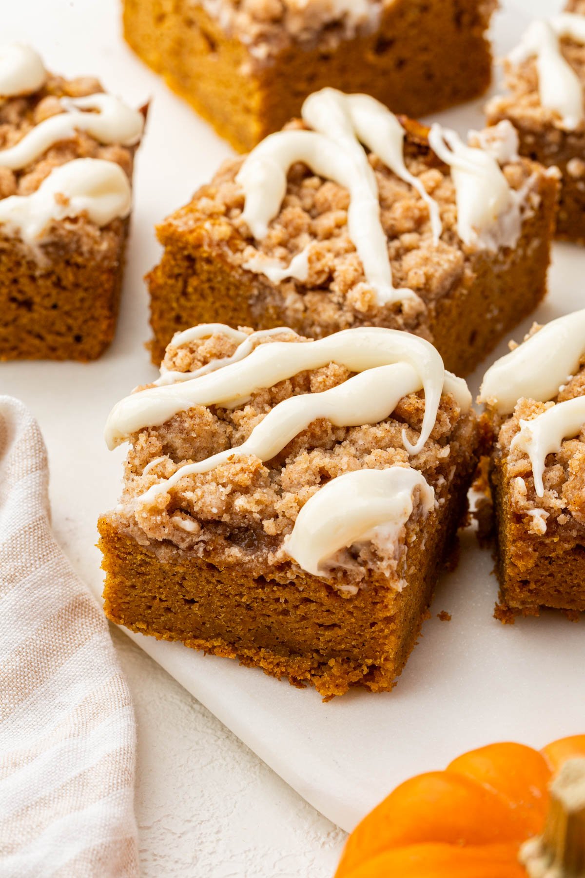 Hero image of a thick, golden slice of gluten-free pumpkin coffee cake with creamy glaze and crumb topping.