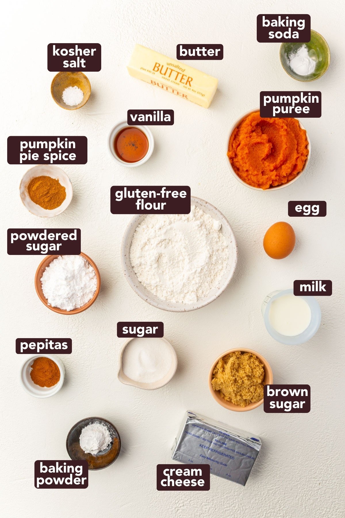 Overhead view of labeled ingredients for gluten-free pumpkin coffee cake including pumpkin purée, gluten-free flour, brown sugar, and cream cheese.