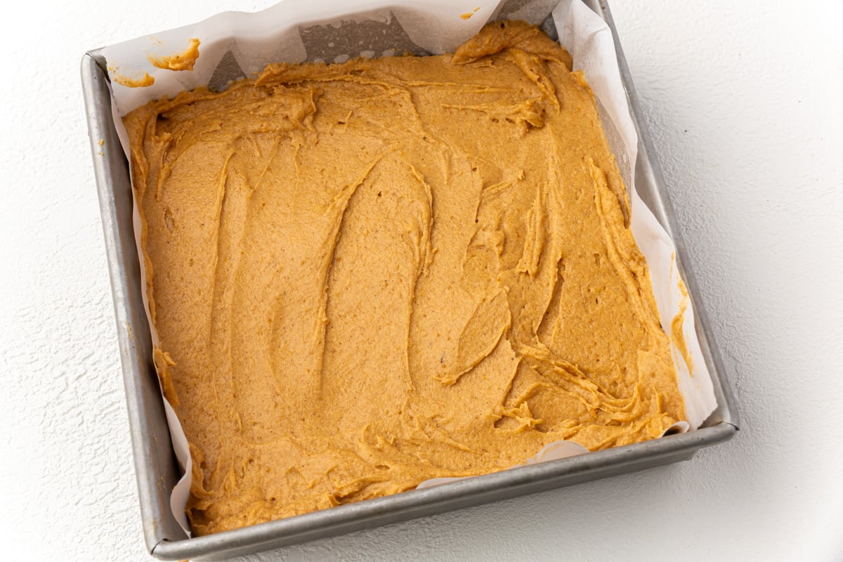 Evenly smoothed pumpkin coffee cake batter in baking pan ready for streusel topping.