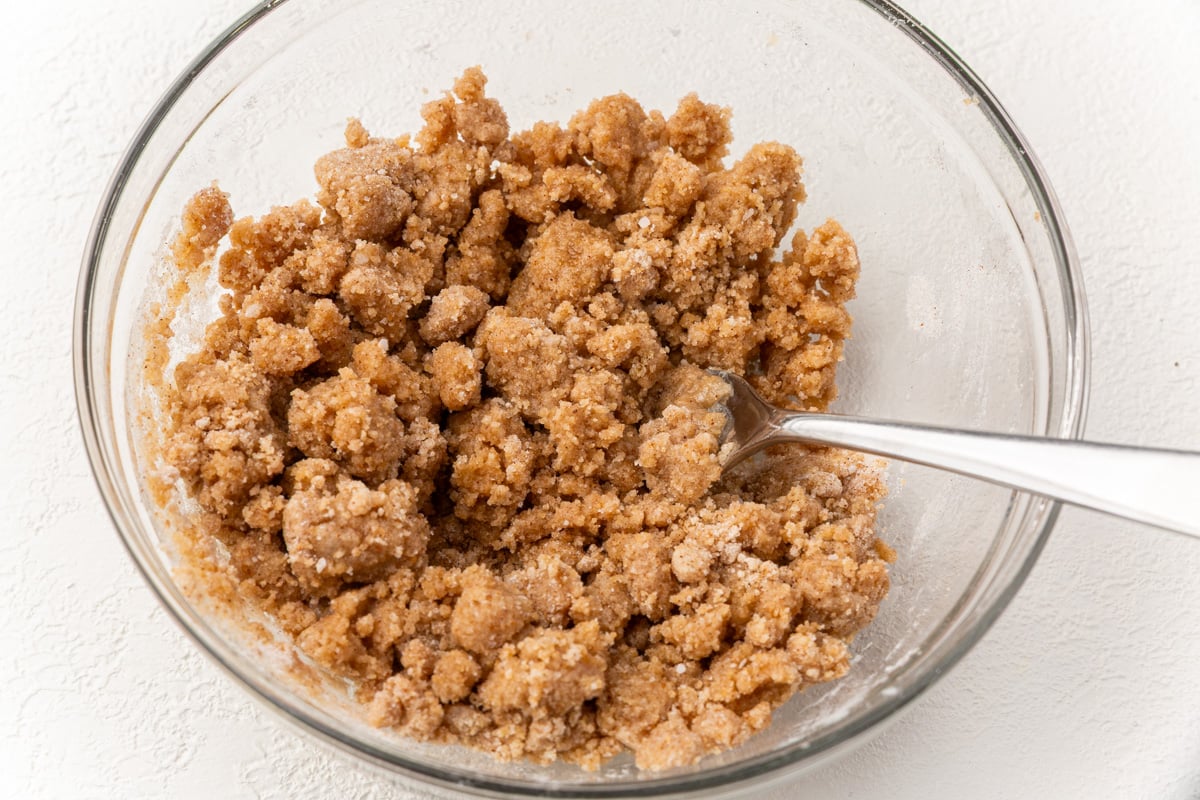 Cinnamon streusel topping mixture in a bowl with a spoon, ready to sprinkle over pumpkin coffee cake.