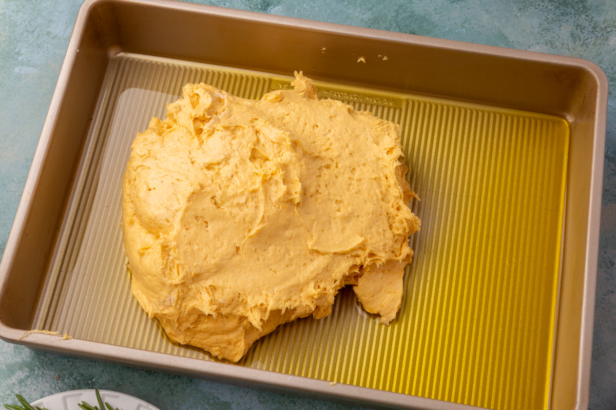 Pumpkin focaccia dough placed in an oiled baking pan before spreading.