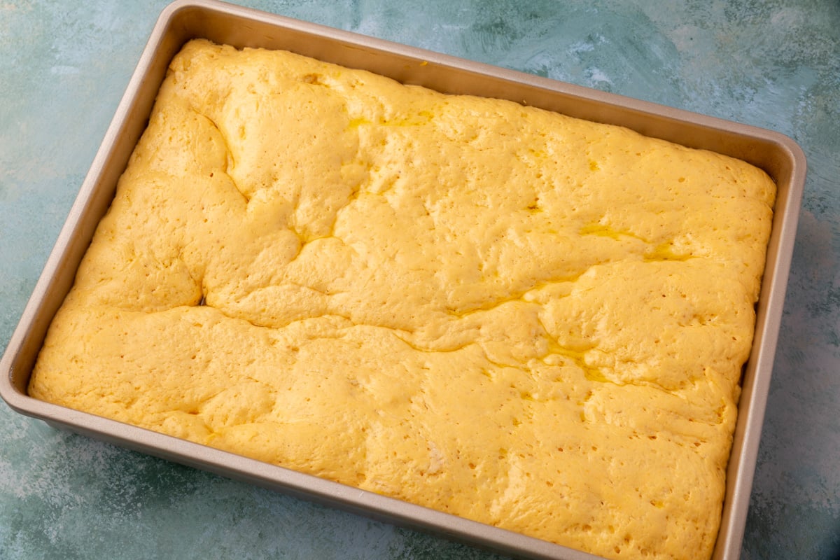 Pumpkin focaccia dough risen and fluffy in the pan before baking.