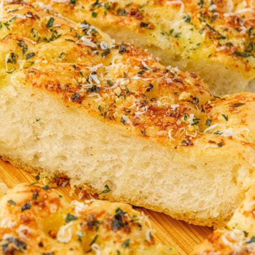 Close-up slice of gluten-free garlic butter focaccia showing light airy crumb texture and golden buttery crust with fresh parsley.