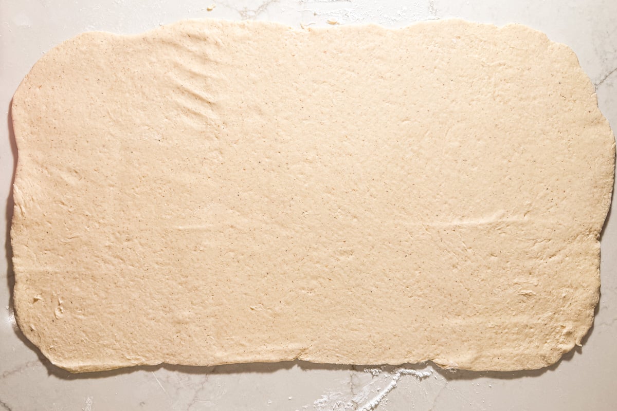 Rolled-out rectangle of gluten-free dough on a lightly floured surface.
