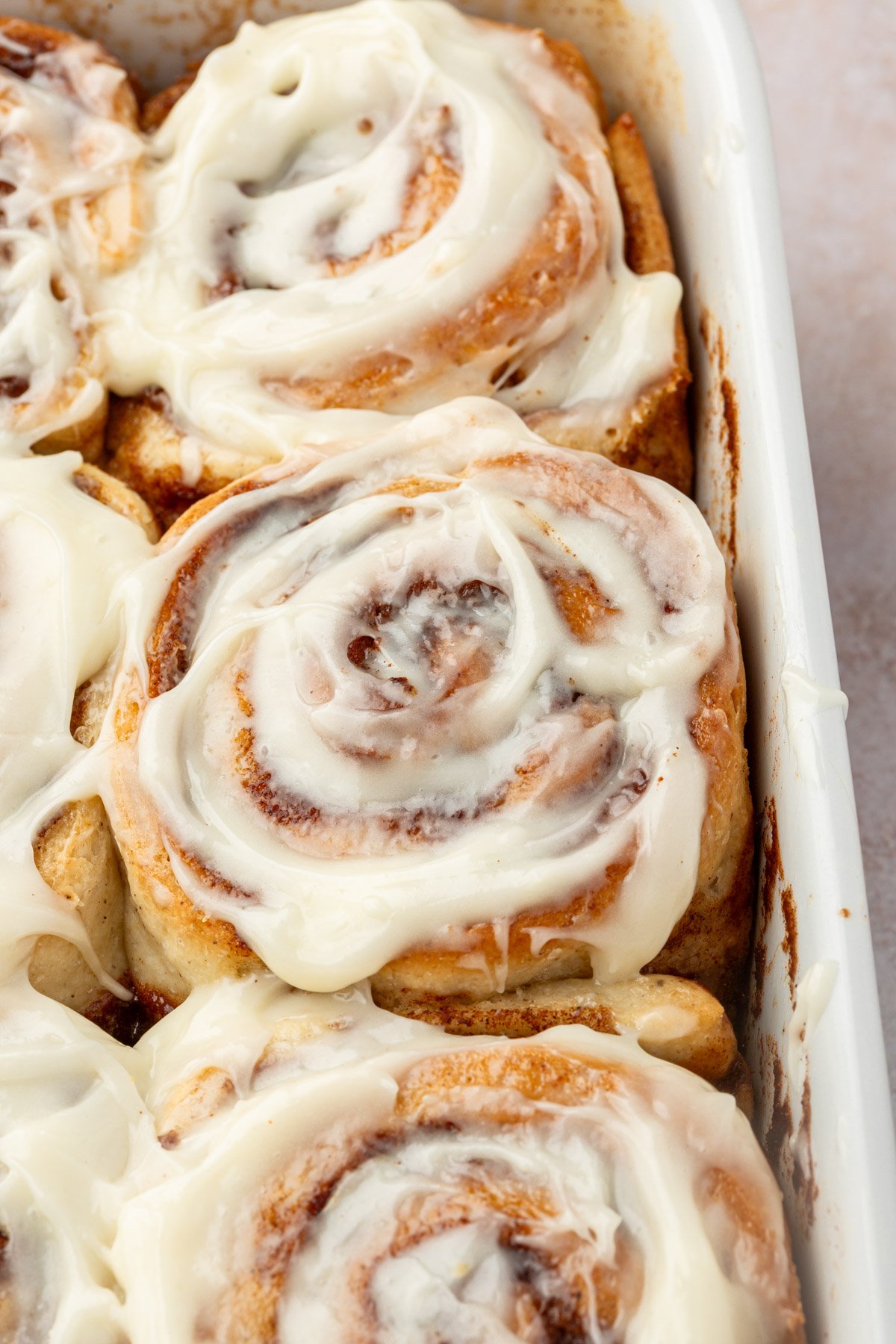 Overhead view of golden brown gluten-free cinnamon rolls baked in a white dish.