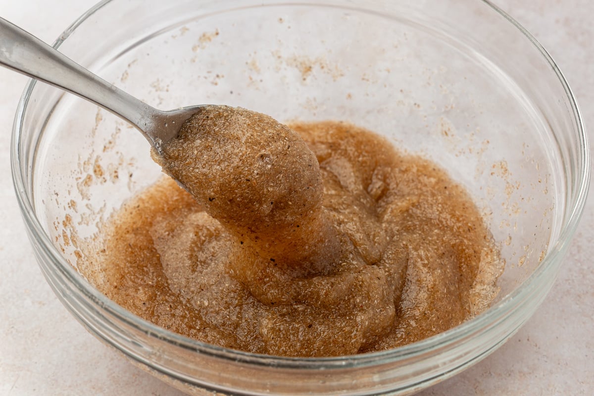 Close-up of hydrated psyllium husk mixture in a glass bowl, with a spoon lifting the thick, gel-like texture.