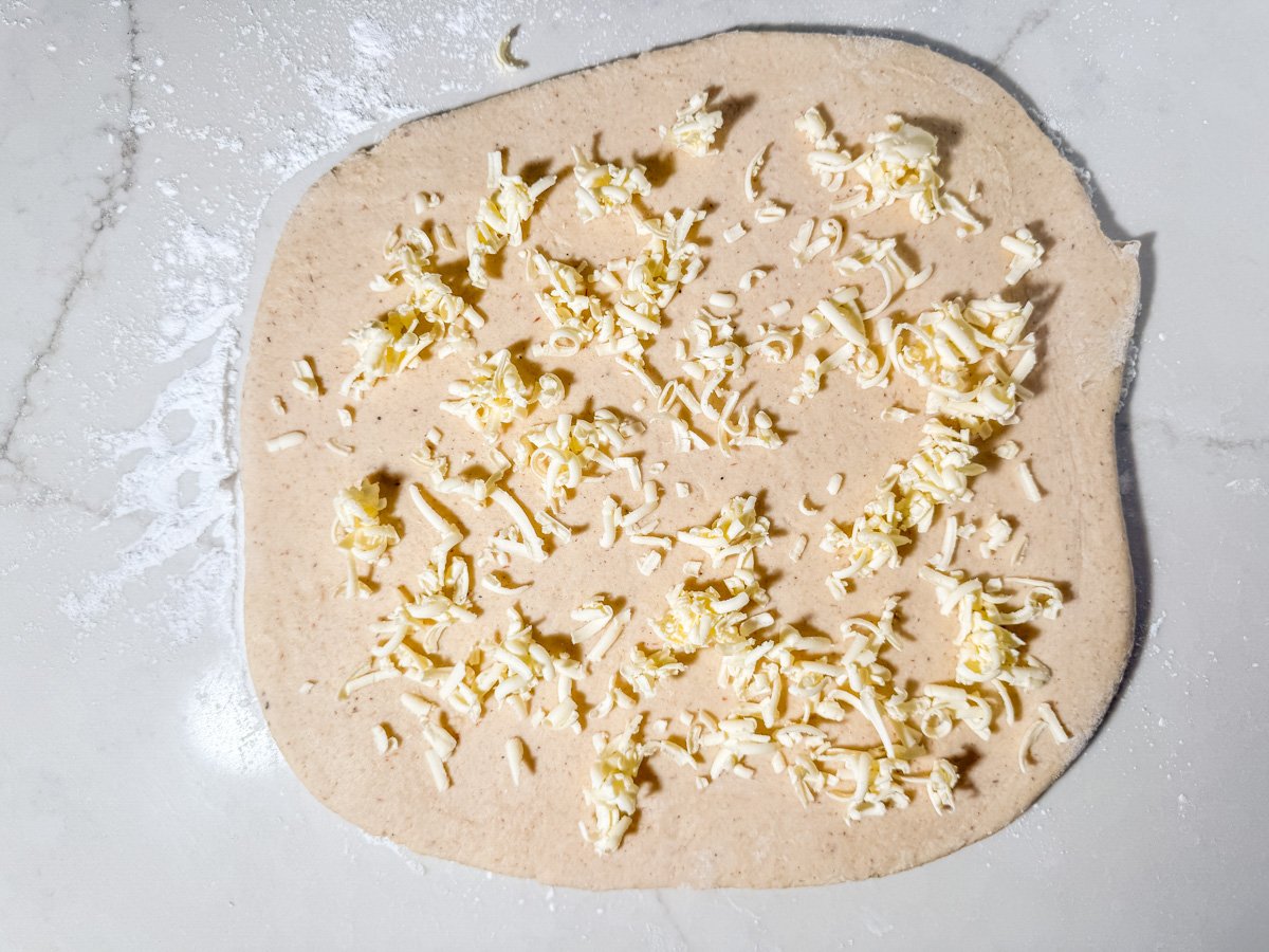 Frozen grated butter scattered across rolled out gluten-free dough for lamination.