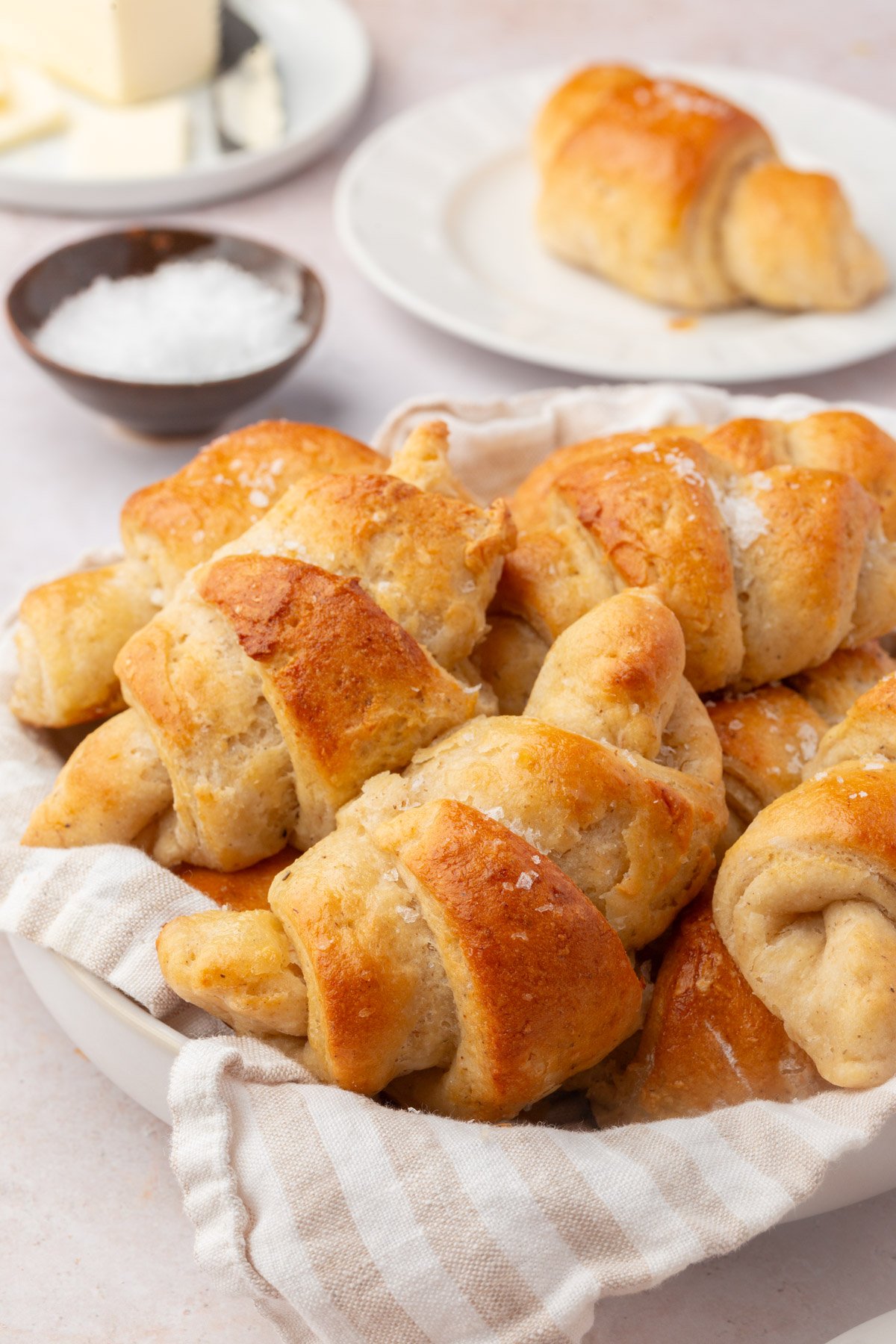 Gluten-free crescent rolls piled in a basket lined with a linen cloth.