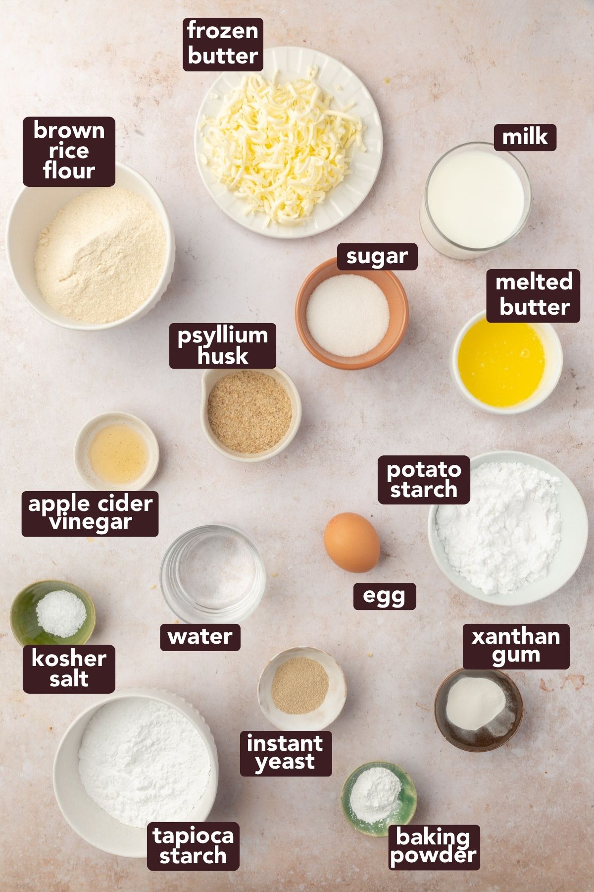 Overhead view of ingredients for gluten-free crescent rolls including brown rice flour, frozen butter, psyllium husk, and starches.