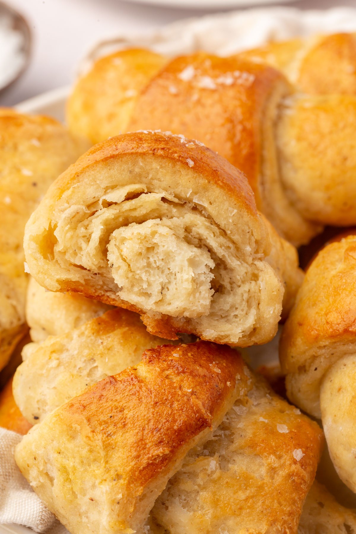 Gluten-free crescent roll torn in half showing flaky laminated layers inside.