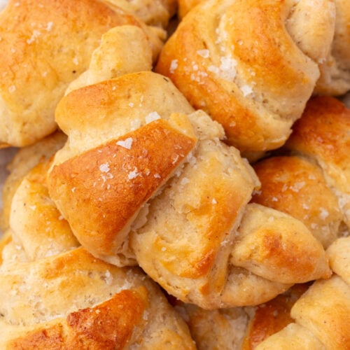 Overhead shot of gluten-free crescent rolls piled in a bowl with flaky salt.