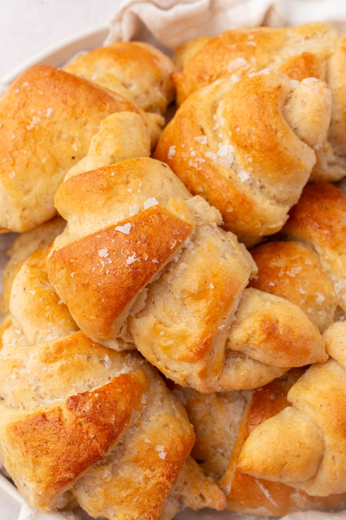 Overhead shot of gluten-free crescent rolls piled in a bowl with flaky salt.
