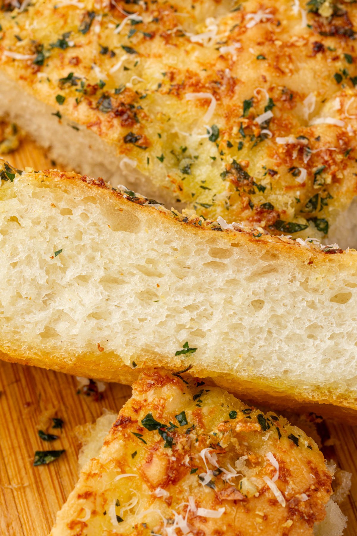 Angled slice of gluten-free garlic butter focaccia displaying soft interior crumb and crispy golden parmesan crust.