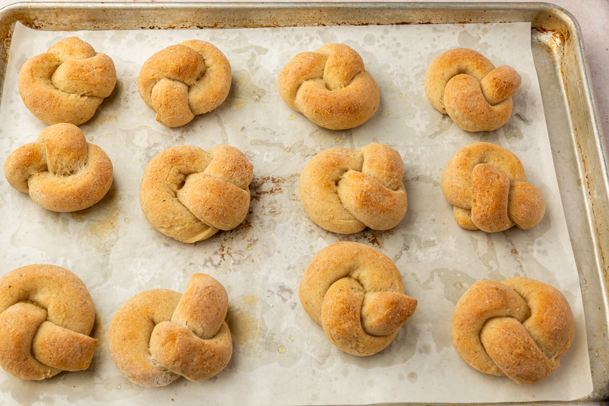 Gluten-free garlic knots baked without butter, lightly browned on a sheet pan.