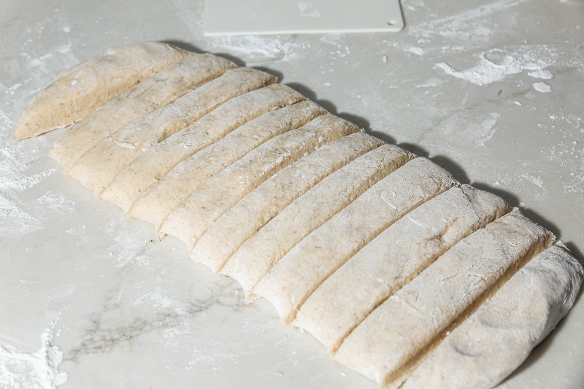 Gluten-free dough rolled into a rectangle and cut into long strips for shaping garlic knots.