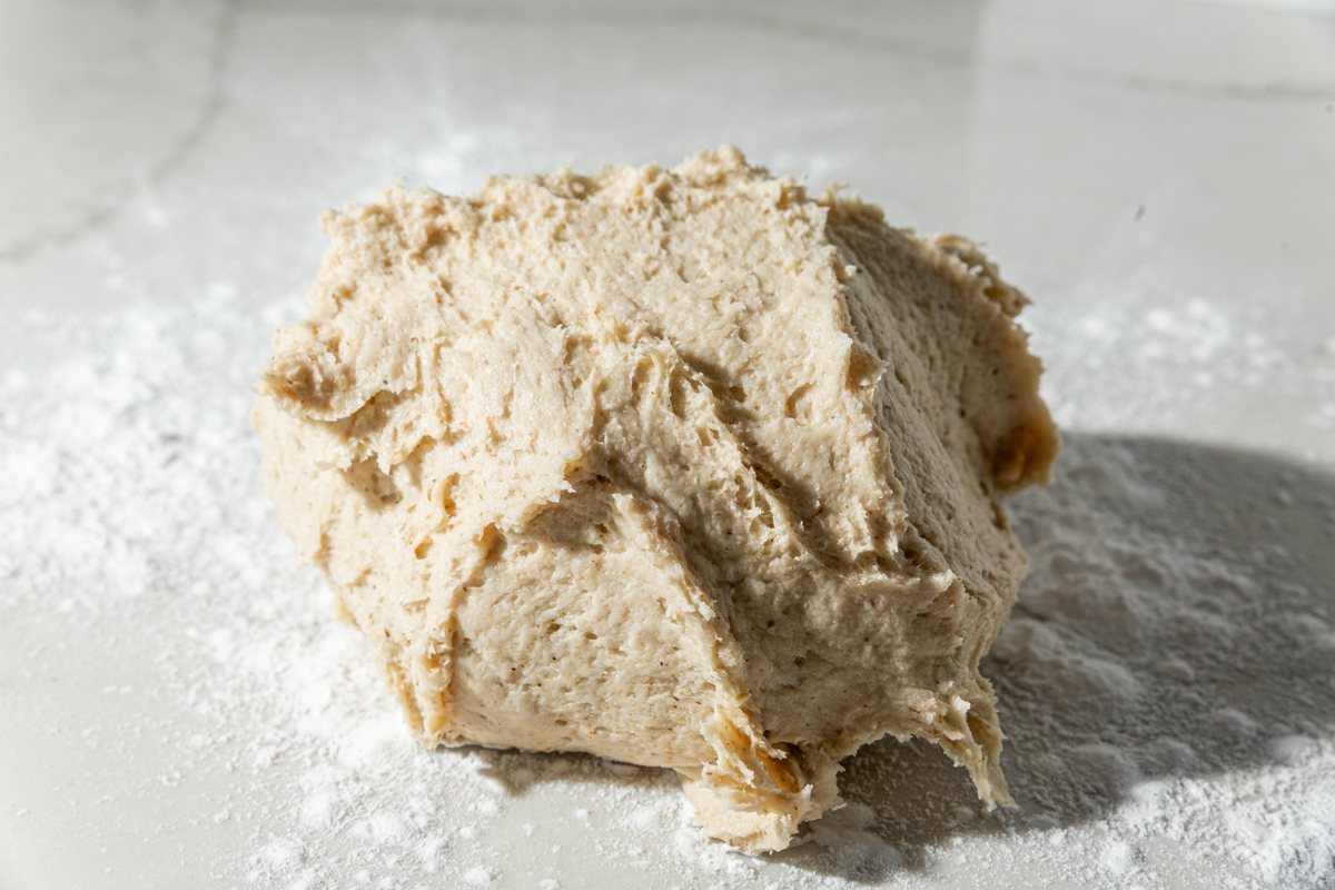 Sticky gluten-free garlic knot dough resting on a lightly floured countertop.