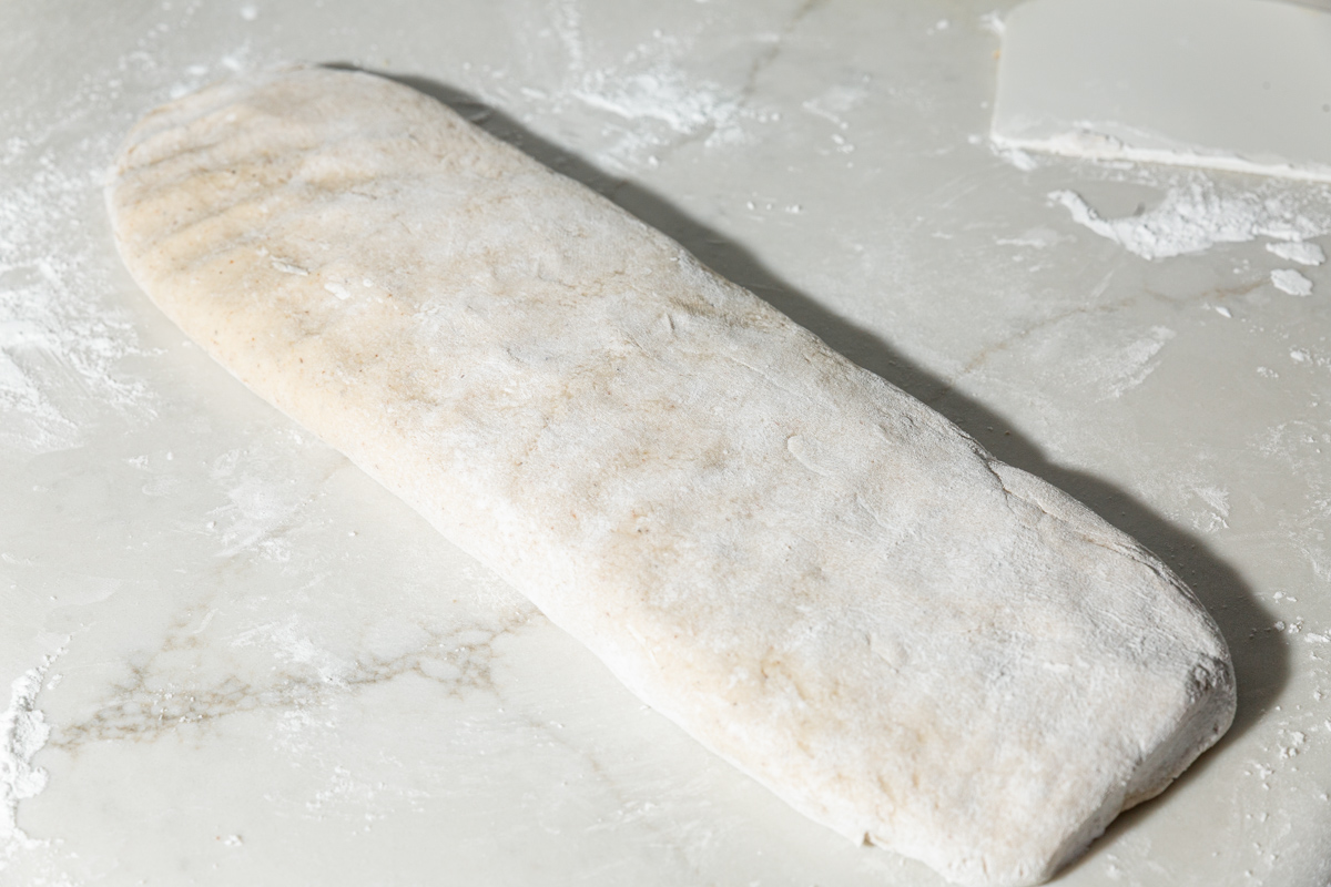 Gluten-free dough patted into a floured rectangle, ready to be cut into strips.