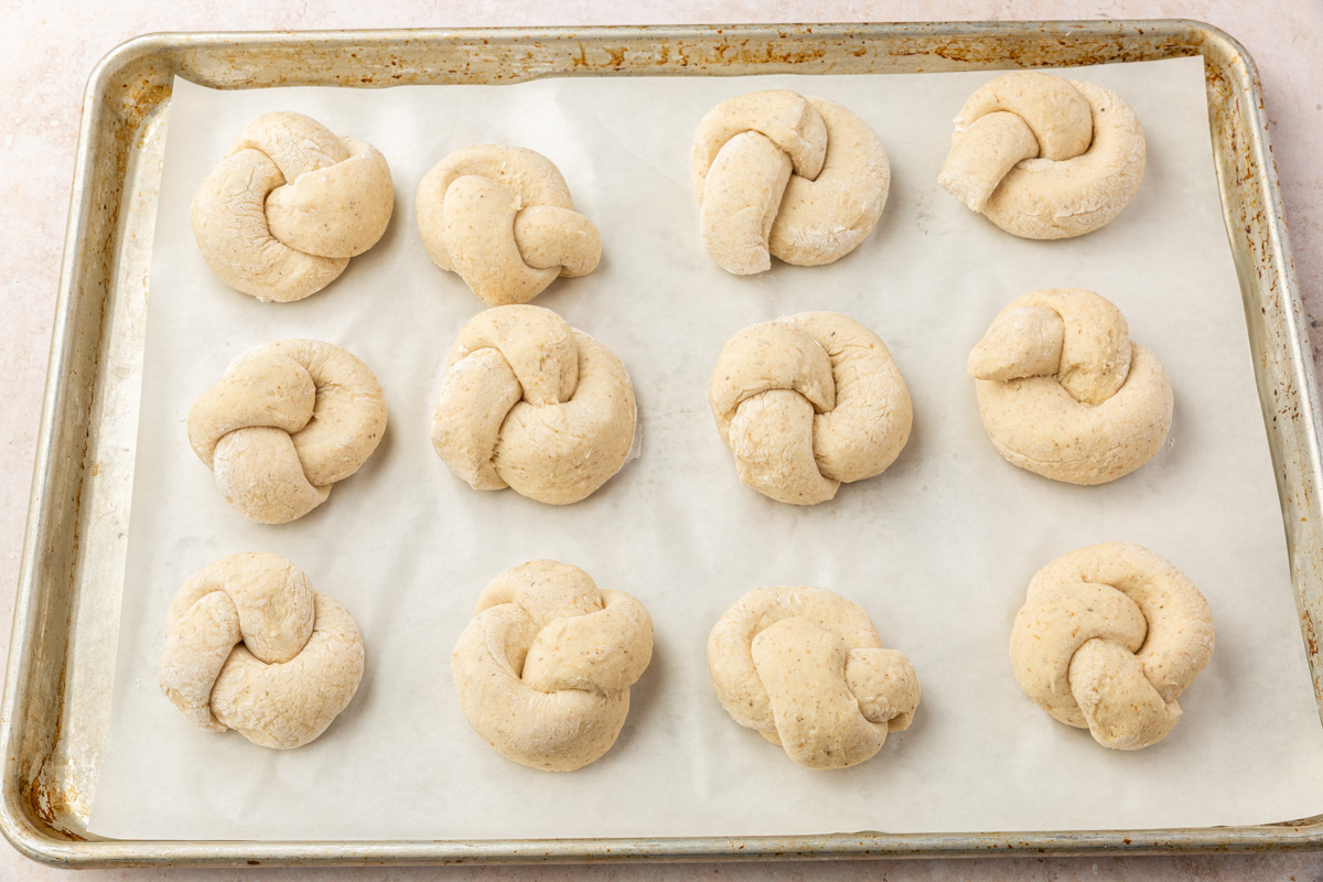 Shaped gluten-free garlic knot dough after rising on a parchment-lined baking sheet, ready to bake.