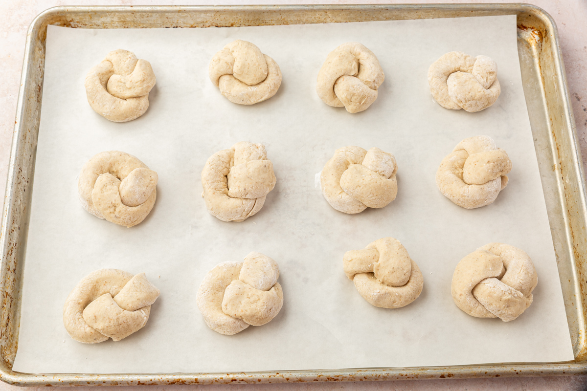 Freshly shaped gluten-free garlic knot dough placed on a parchment-lined baking sheet before proofing.