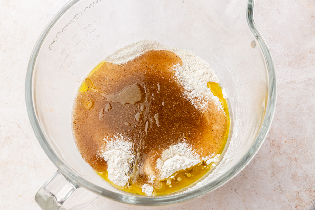Psyllium gel and olive oil added to a bowl of gluten-free flour mixture before mixing into dough.