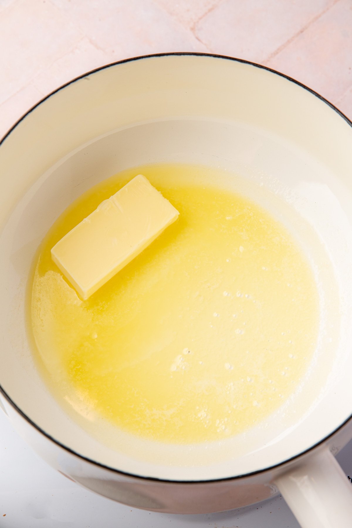 Butter melting in a white saucepan on the stove to start making a gluten-free roux.