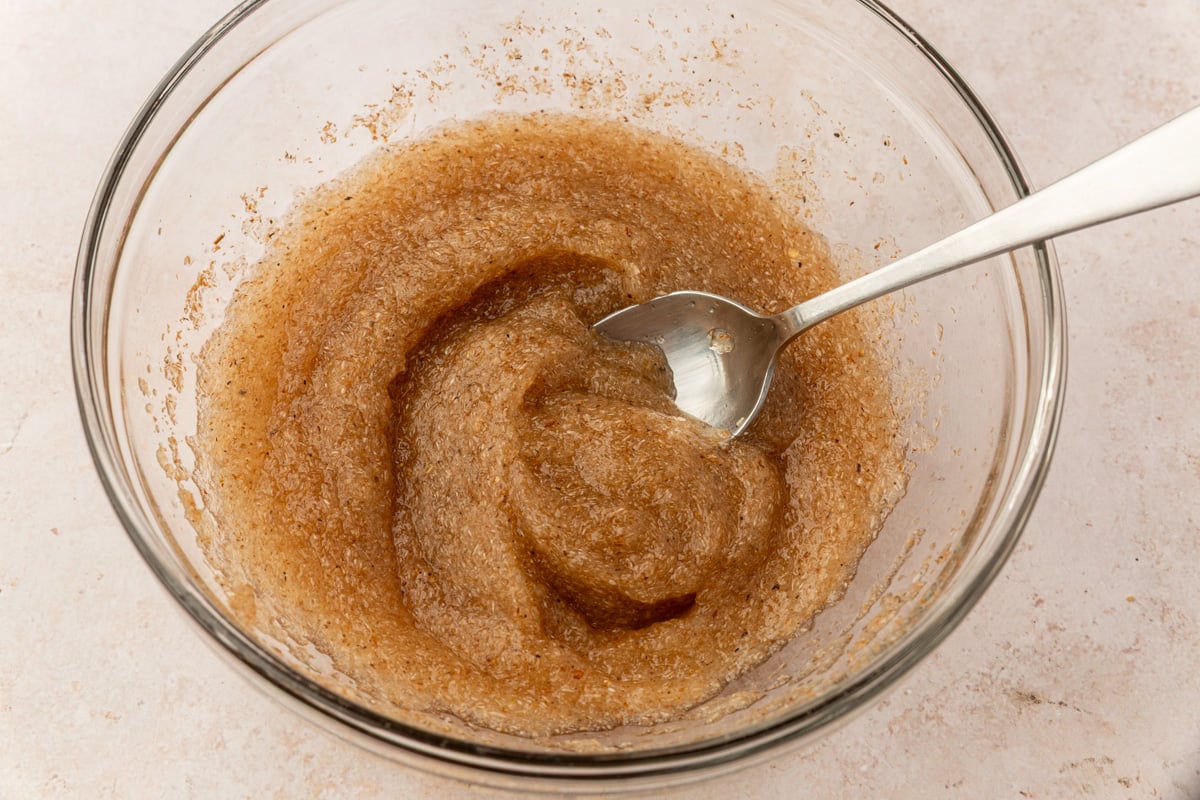 Brown psyllium husk gel in a glass bowl after mixing with warm water, forming a thick texture.