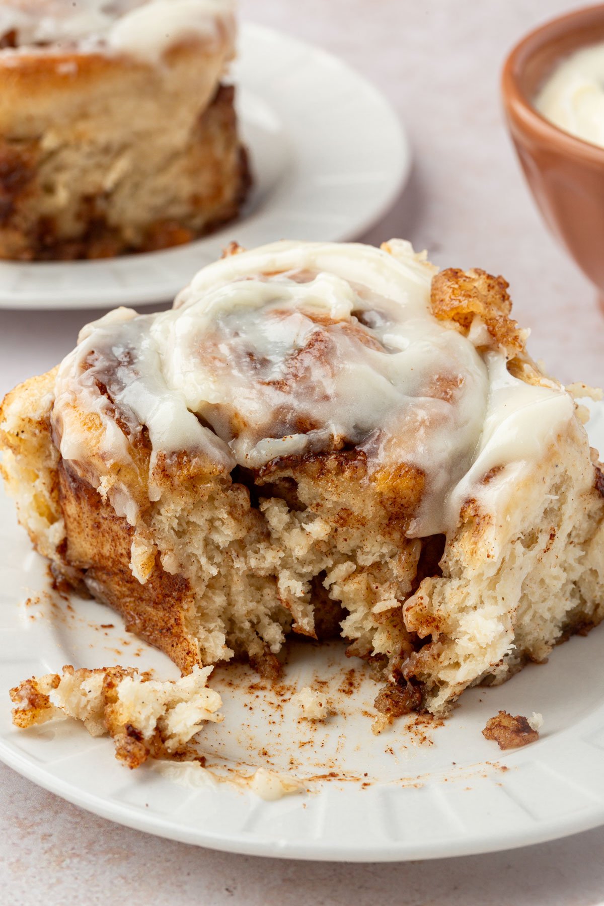 Soft, fluffy gluten-free cinnamon roll with cream cheese frosting and a bite removed to reveal tender layers.
