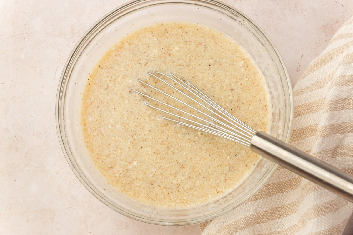 Wet ingredients for gluten-free dinner rolls whisked together in a glass bowl until smooth.