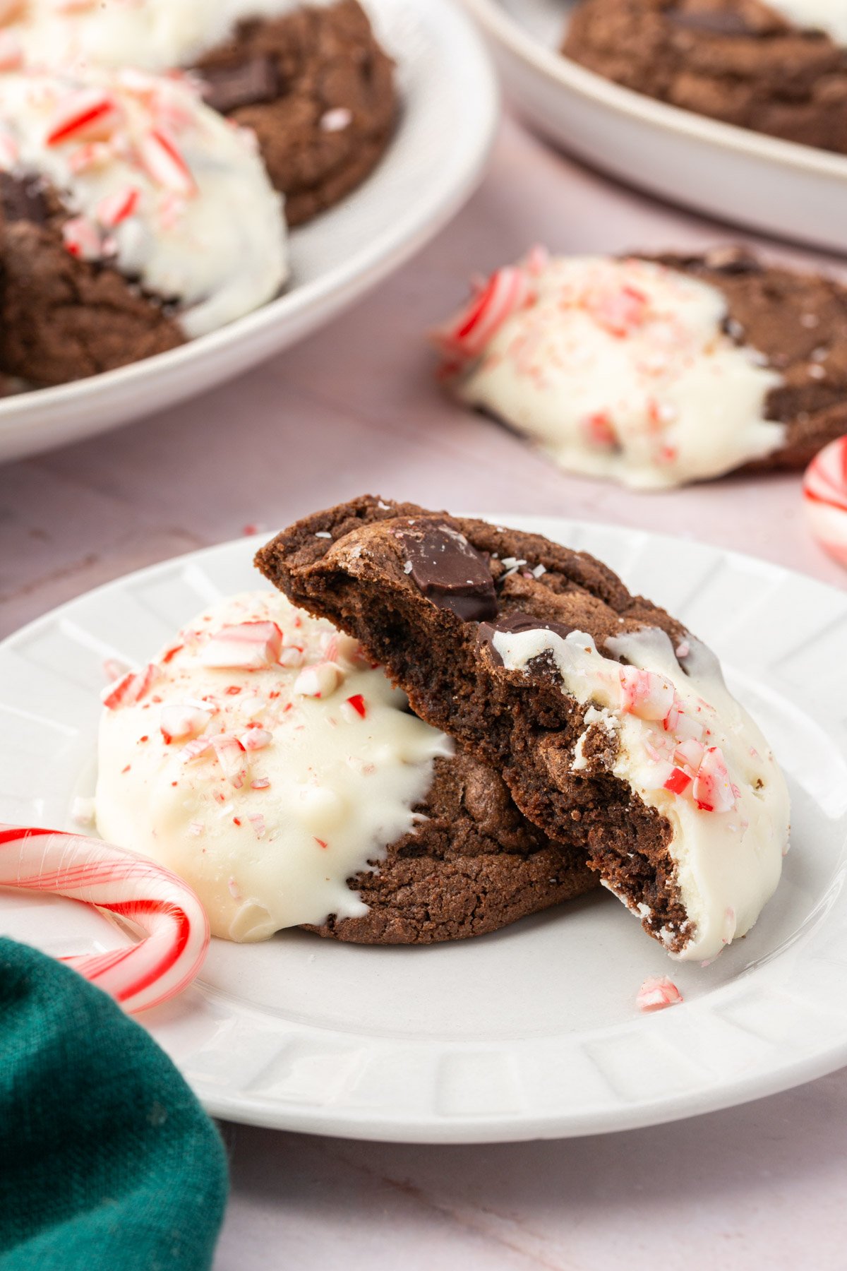 Gluten-free chocolate peppermint cookie broken in half showing fudgy interior with chocolate chunks and white chocolate coating.