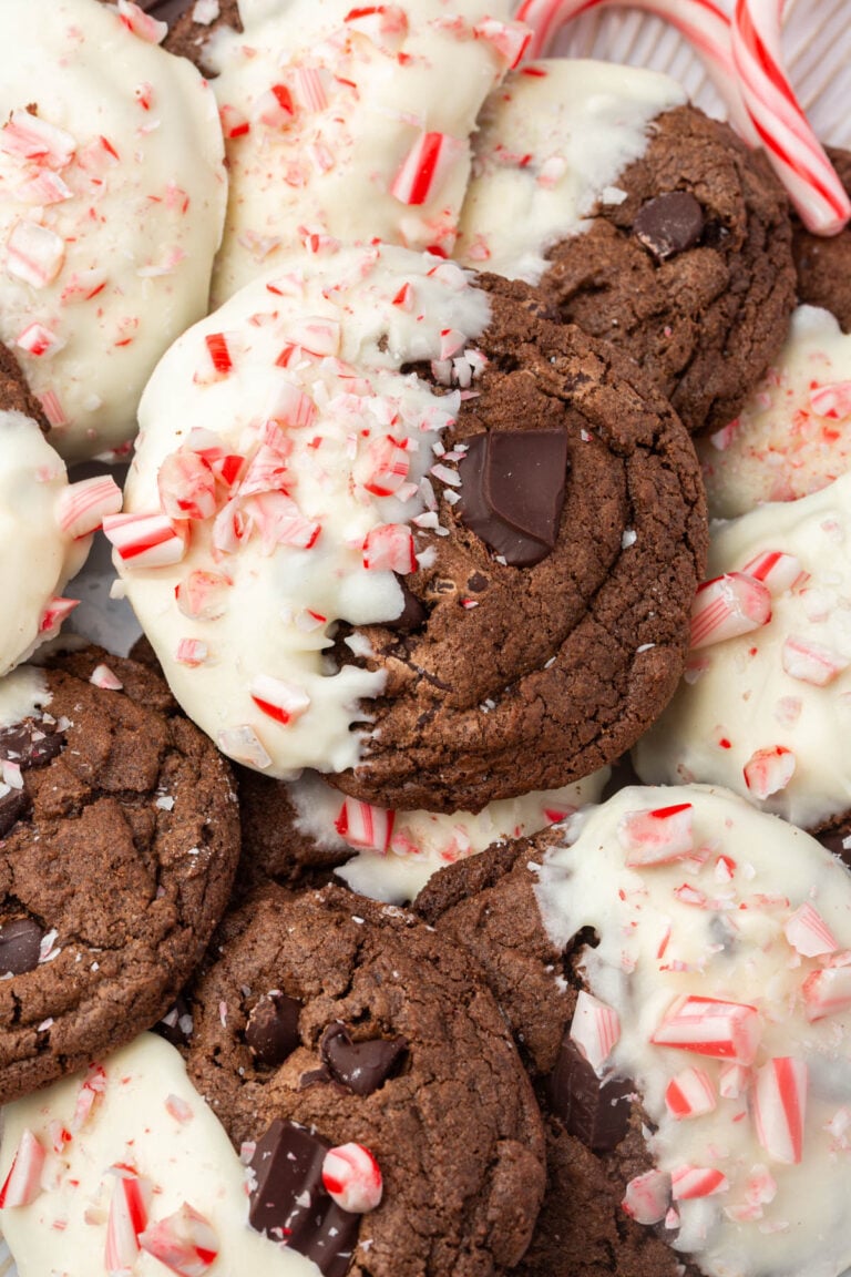 Close-up of gluten-free chocolate peppermint cookies with white chocolate coating, crushed candy canes, and dark chocolate chunks.