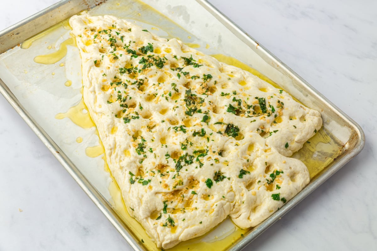 Risen Christmas tree focaccia dimpled with fingers and topped with garlic butter and fresh parsley.