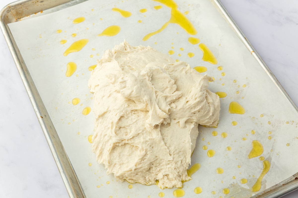 Gluten-free focaccia dough placed on oiled parchment paper on baking sheet before shaping into tree.