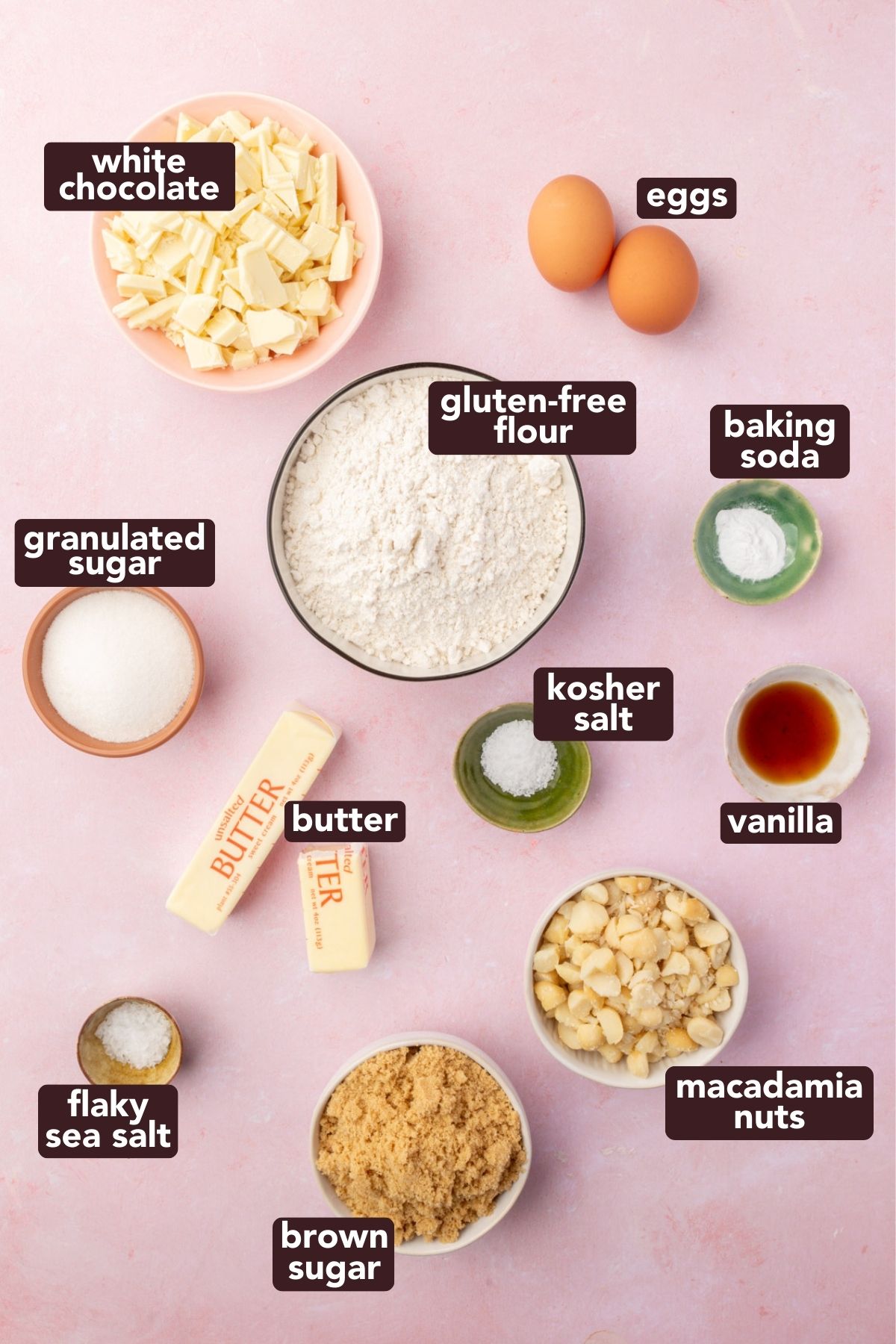 Flatlay of gluten-free white chocolate macadamia cookie ingredients, including flour, sugars, butter, eggs, white chocolate, and macadamia nuts.