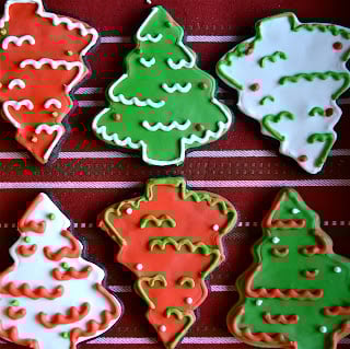 Gluten-free chocolate cut out cookies decorated with red, green, and white royal icing in Christmas tree shapes.