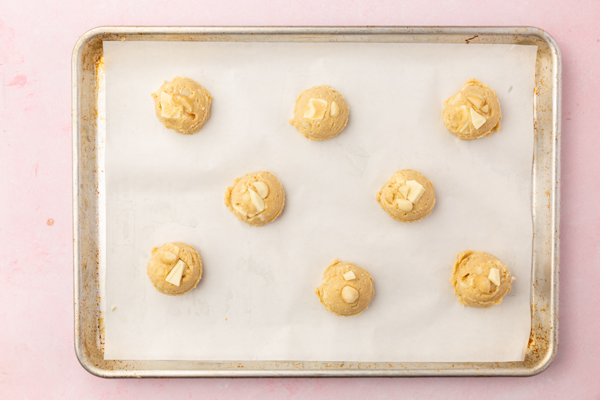 Scooped cookie dough balls arranged on a parchment-lined baking sheet.