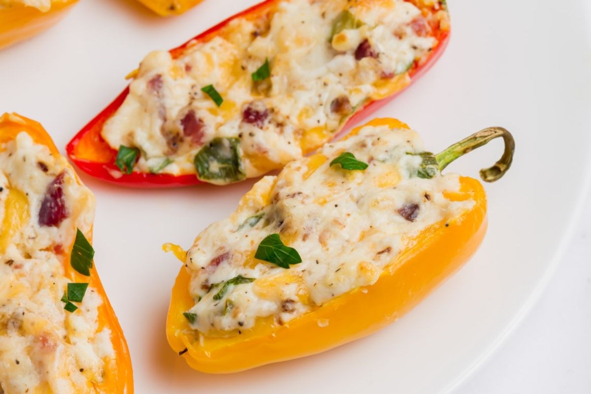 Close-up of stuffed mini peppers with melted cheddar, bacon, and parsley.