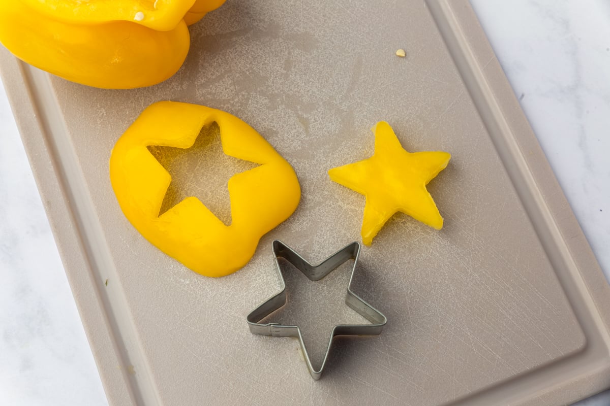 Yellow bell pepper slice with star cookie cutter and cut star for Christmas tree focaccia topper.