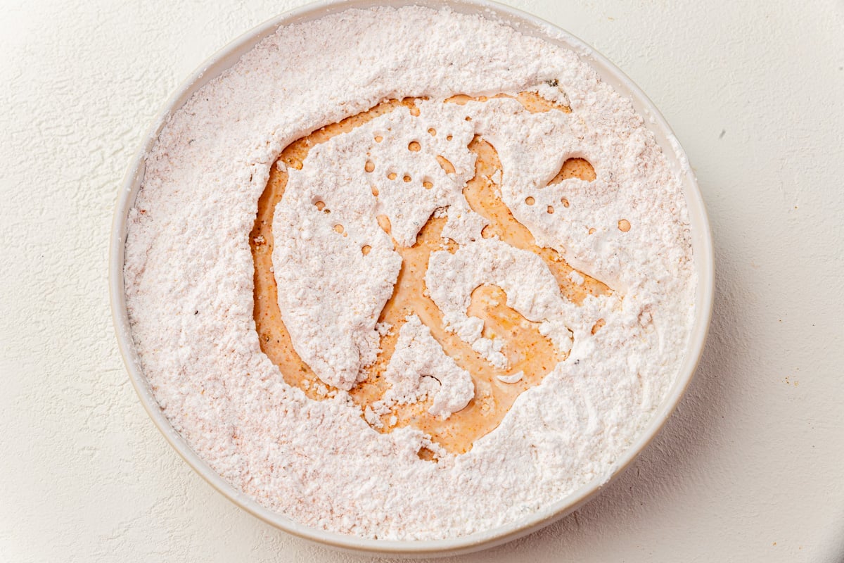 Adding buttermilk marinade to gluten-free flour mixture to create craggy bits.