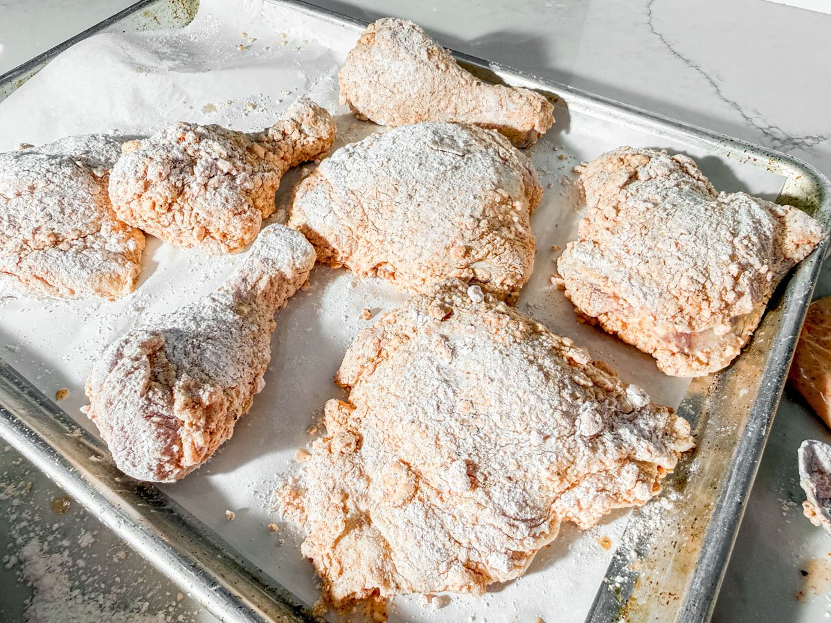 Gluten-free breaded chicken pieces on a baking sheet before frying.