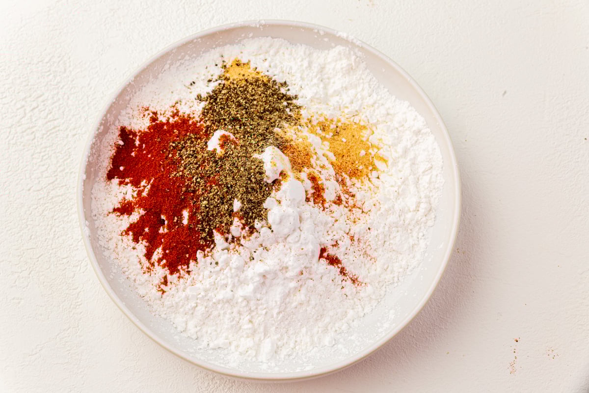Gluten-free flour dredge with rice flour, potato starch, cornstarch and spices in a white bowl.