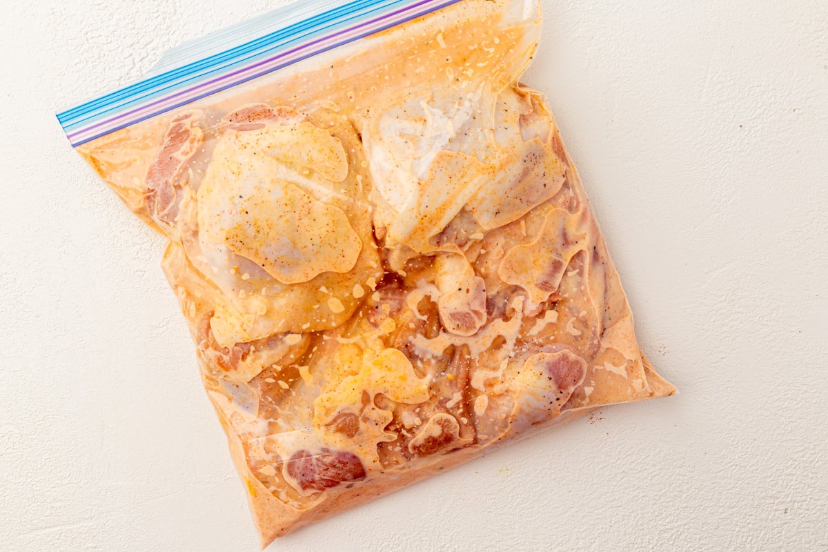 Chicken pieces marinating in buttermilk and pickle juice mixture in ziplock bag.
