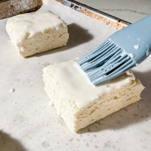 Brushing gluten-free biscuits with buttermilk using a blue silicone pastry brush