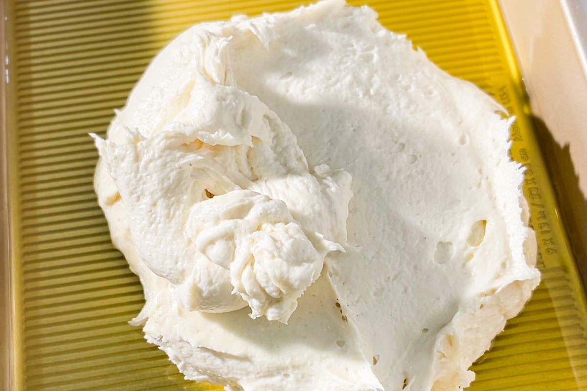 A close-up of gluten-free focaccia dough ball on a baking pan that has been generously oiled with olive oil.