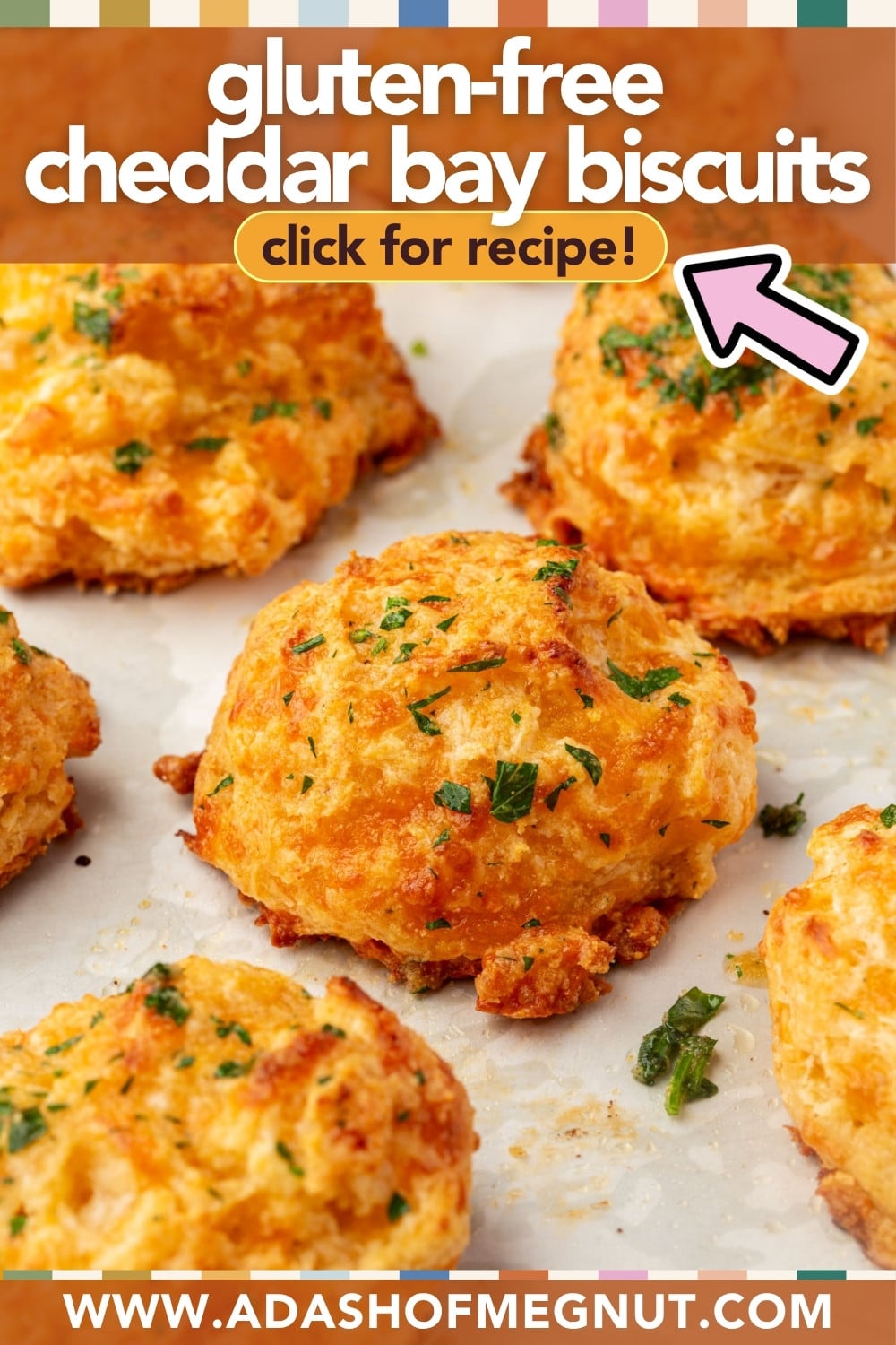 Gluten-free cheddar bay biscuits topped with chopped herbs on parchment paper. Text over image reads: “gluten-free cheddar bay biscuits, click for recipe!” and website “www.adashofmegnut.com” at the bottom.
