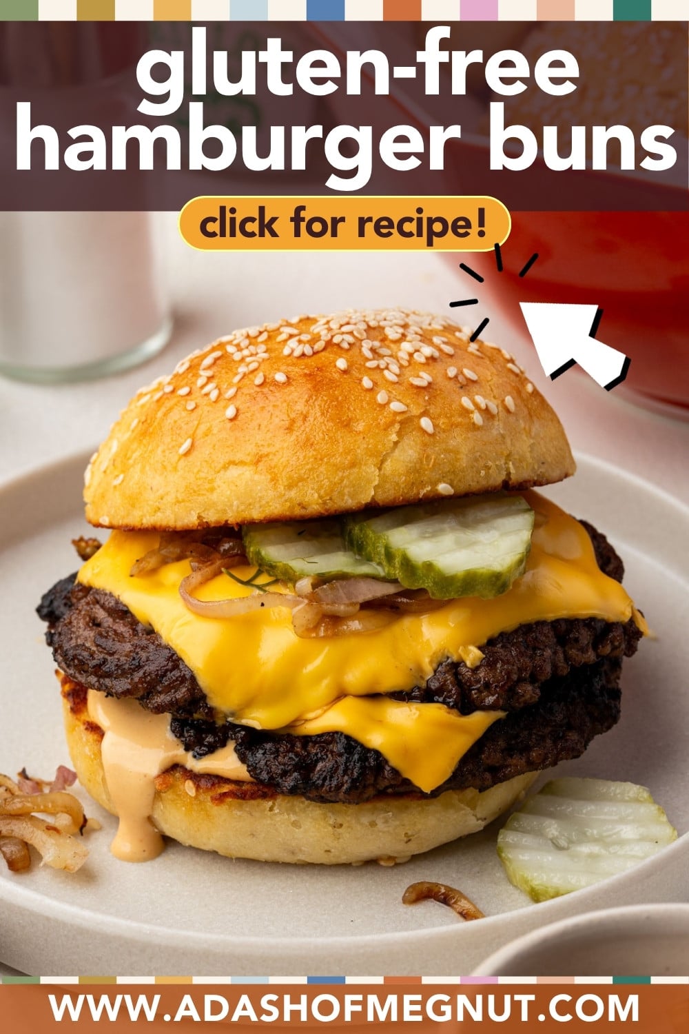 A cheeseburger with a sesame seed gluten-free bun, melted cheese, pickles, grilled onions, and sauce sits on a plate. Text reads gluten-free hamburger buns and click for recipe! with a website link at the bottom.