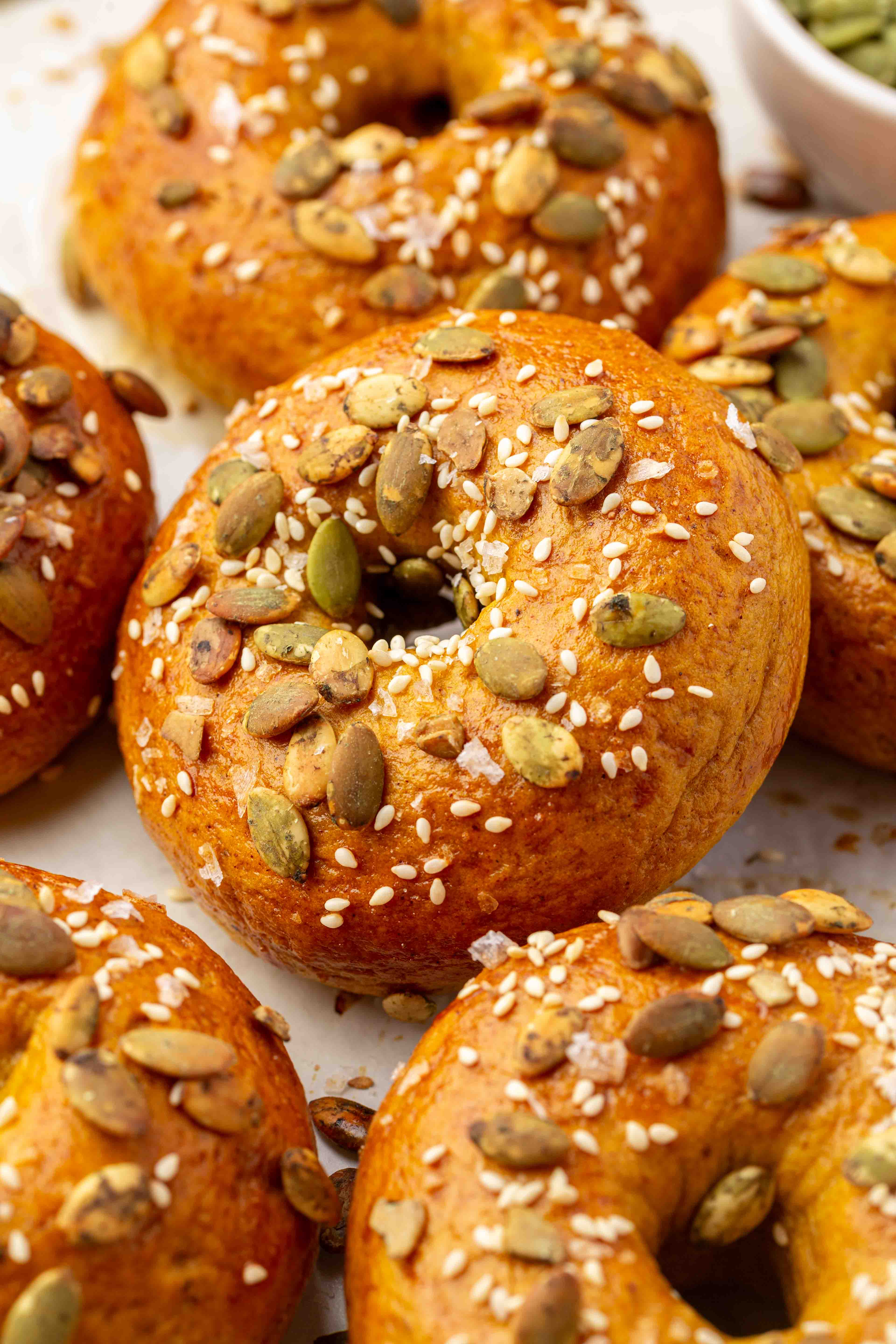 Golden-brown gluten-free pumpkin bagels topped with pumpkin seeds, sesame seeds, and coarse salt.
