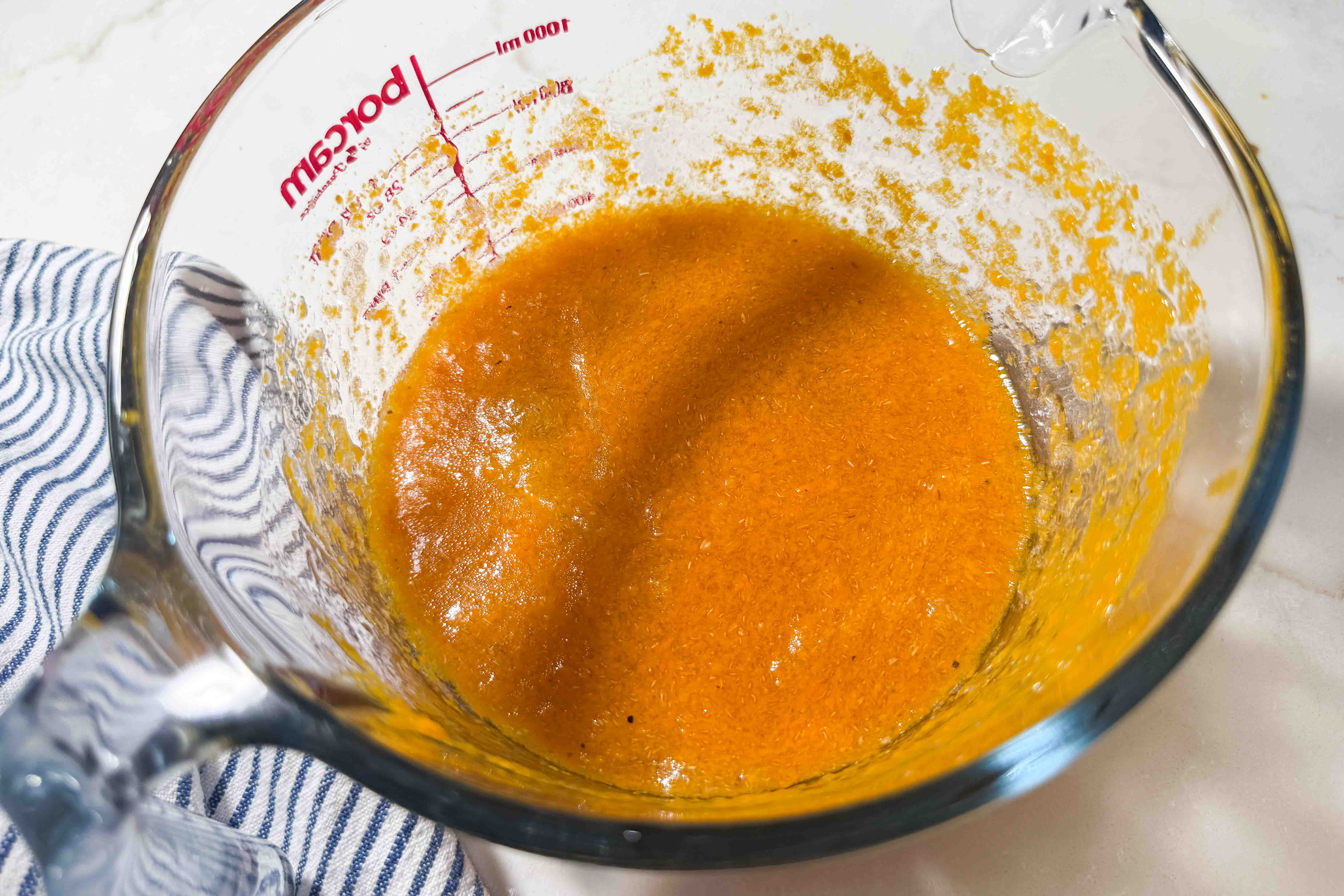 A glass measuring cup filled with a pumpkin puree mixture.