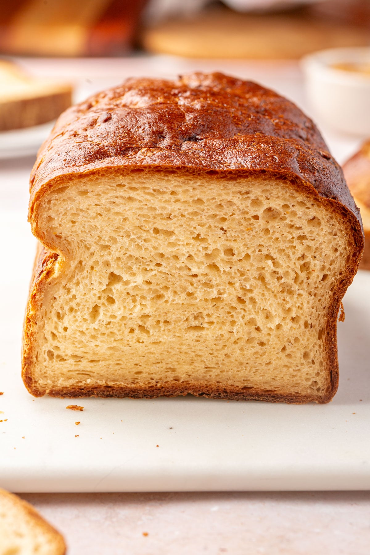 A loaf of sliced gluten-free enriched sandwich bread on a white surface.