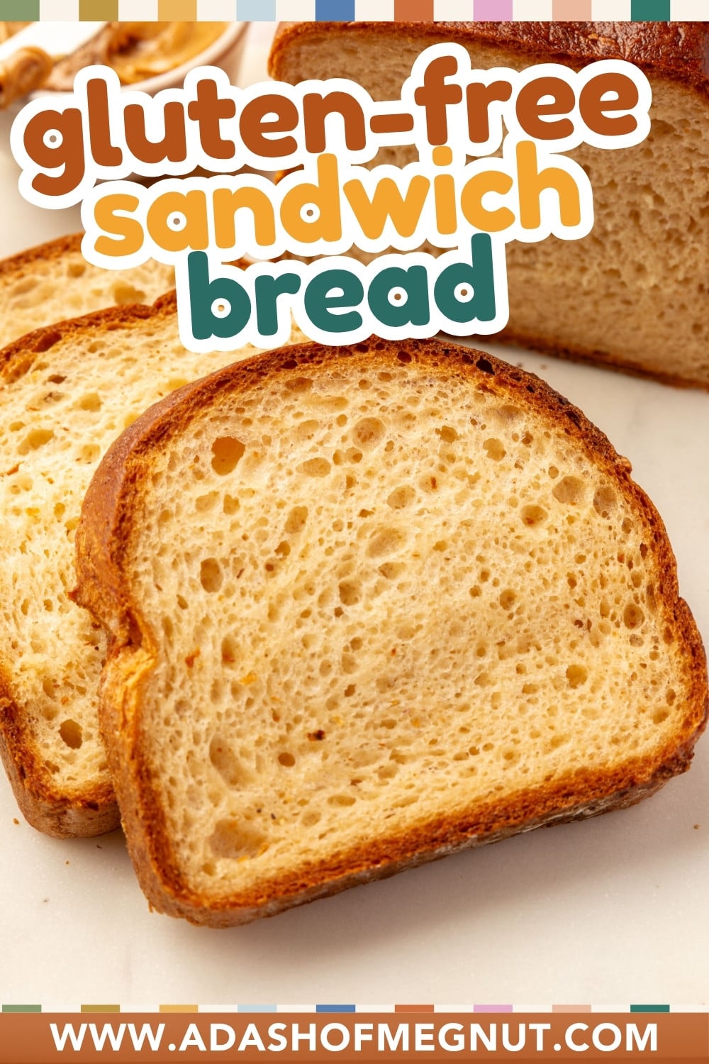 Two slices of gluten-free sandwich bread resting on a white surface in front of a whole loaf.